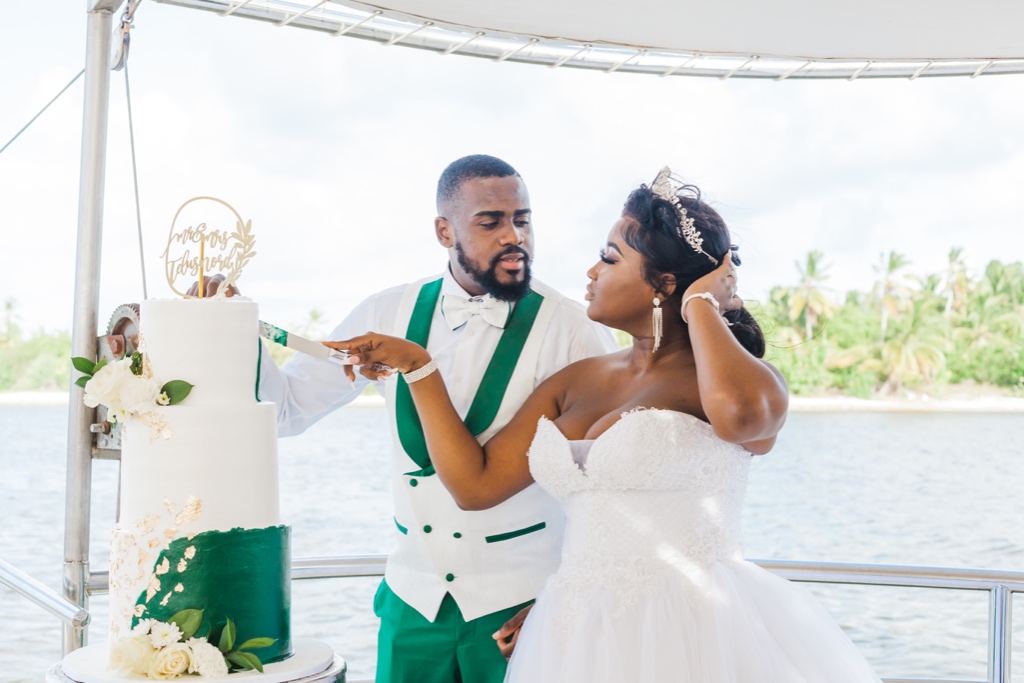 Bride and groom are cutting the cake at the wedding on a boat
